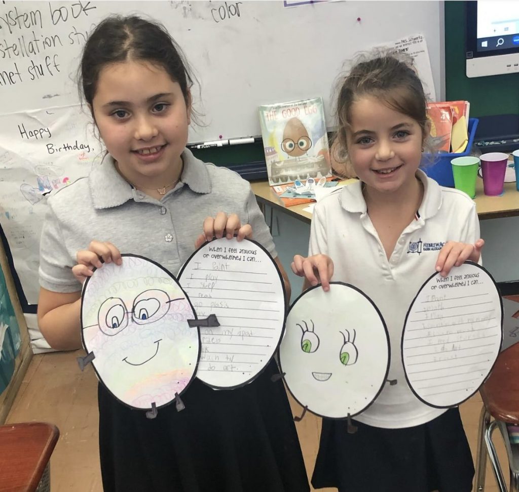 Two happy kids showing their drawings from the workshop.