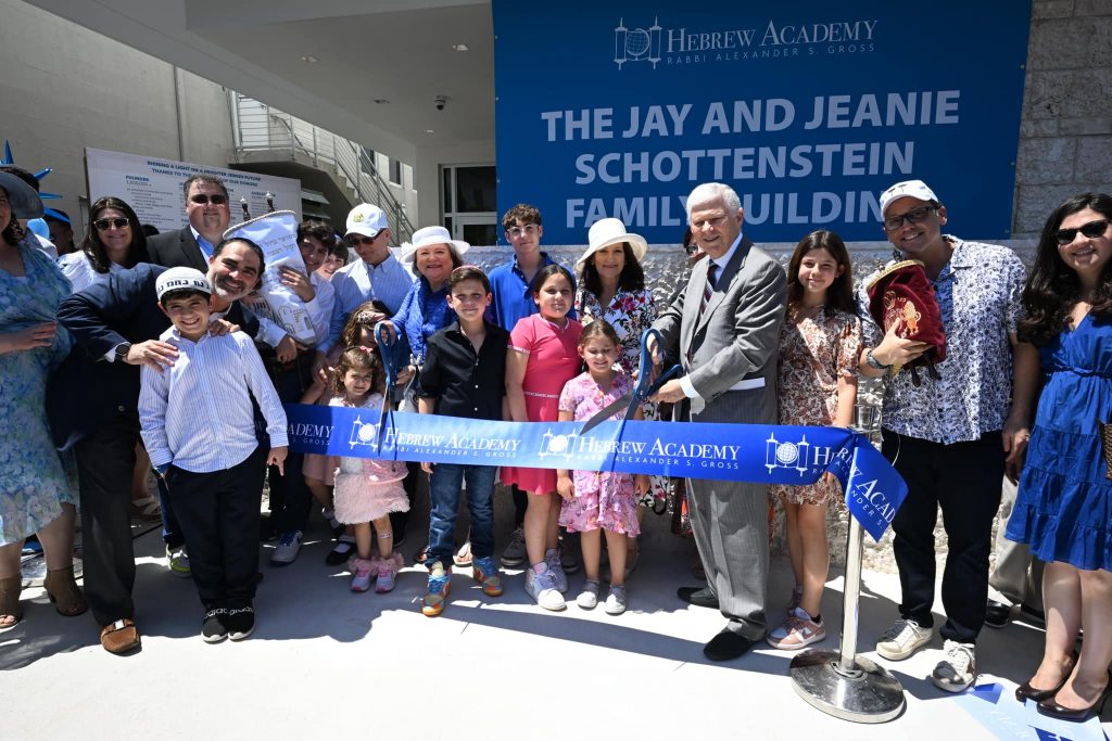 Ribbon-cutting ceremony with smiling kids and adults at new Hebrew offices.