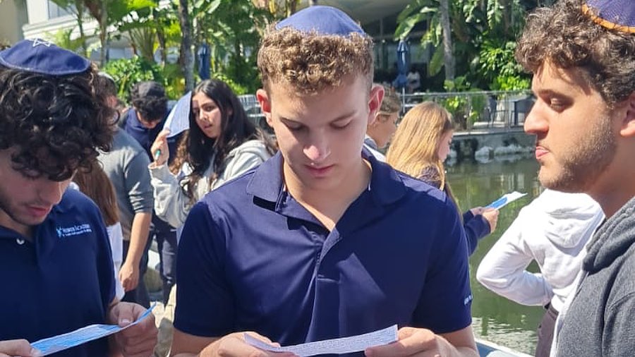 Close-up of a Jewish student reading from a list of paper outdoors with focus and concentration.