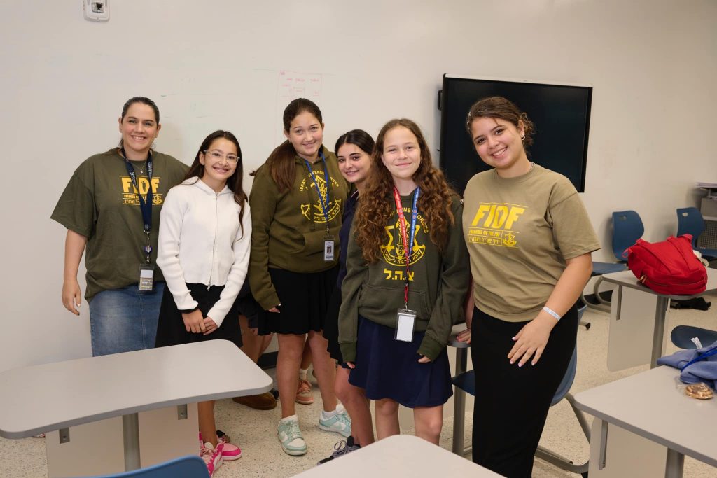 Group of students in a classroom smiling and posing for a photo.