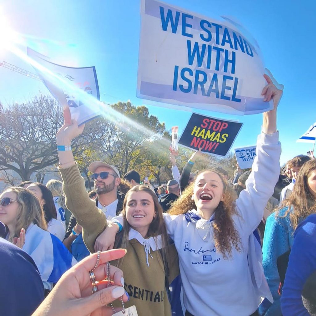 Group of people holding 'We Stand with Israel' signs at a peaceful gathering.