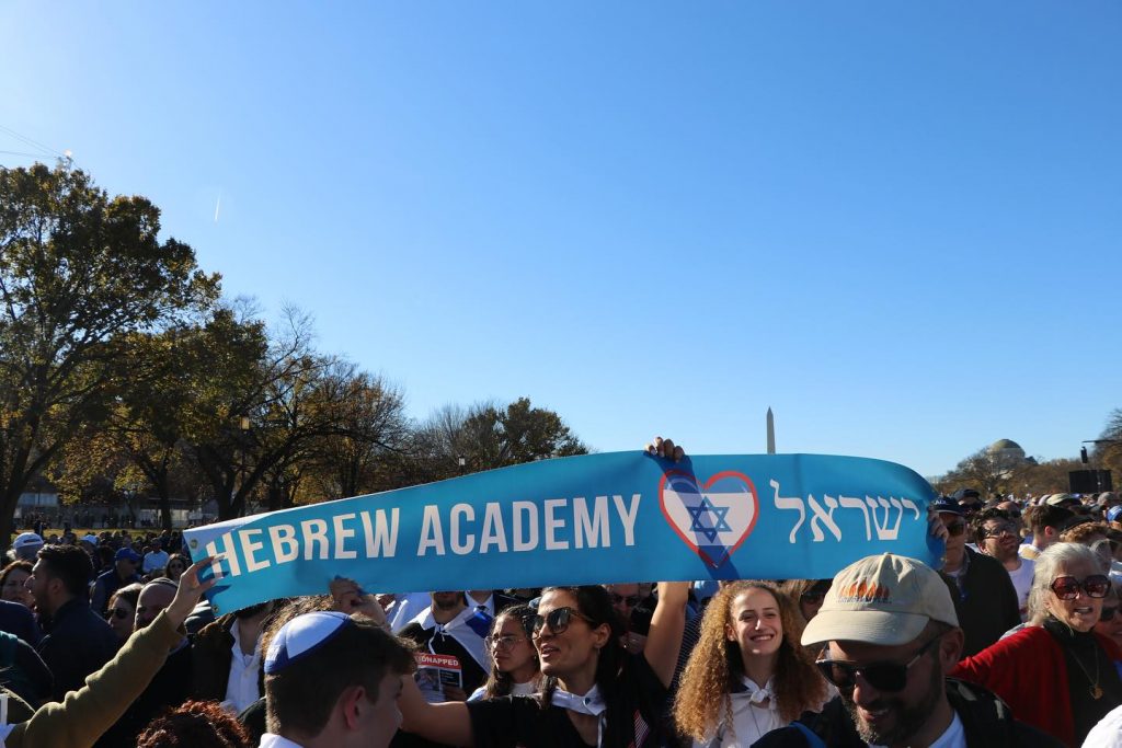 People holding the Hebrew Academy flag in a group gathering.