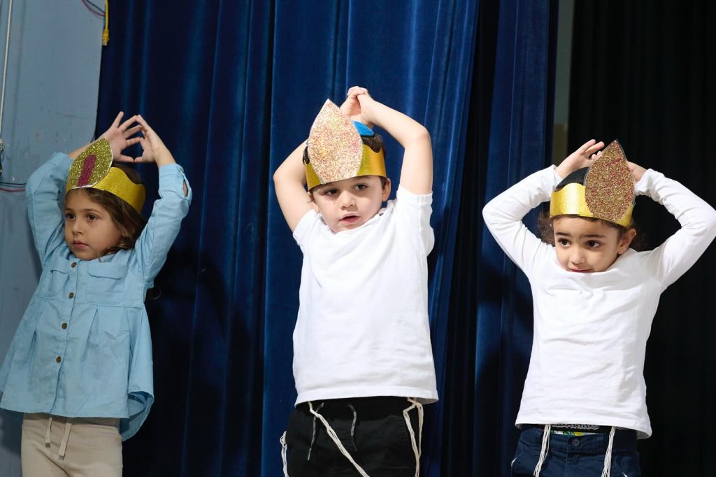 Kids at an event with their hands raised above their heads.