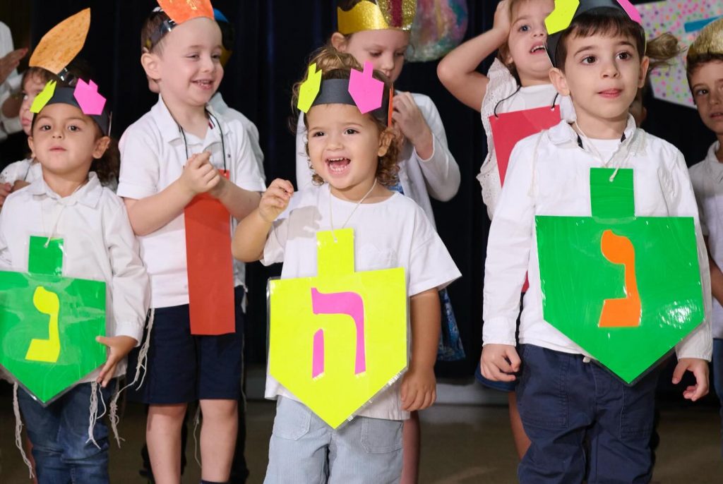 Group of kids smiling and happy at the Festival of Lights show, wearing event-themed clothing.