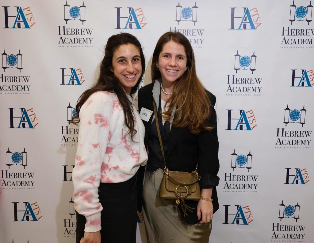 Two women smiling at a Hebrew Academy HA PTSA event.