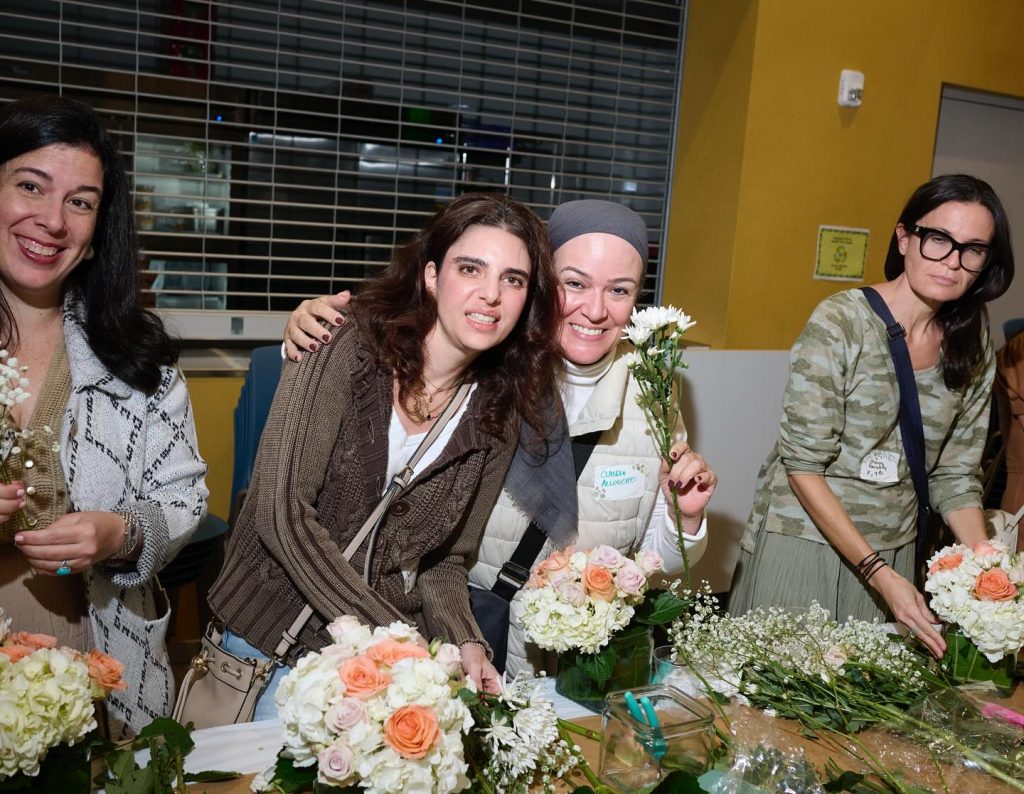 Two women smiling at a Hebrew Academy HA PTSA event with flowers in their hands.