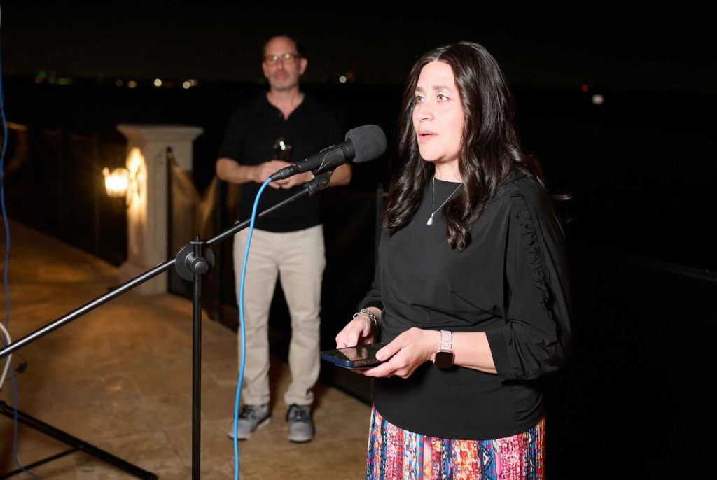 Adult female speaking into a microphone at the Memorable Evening with Hebrew Academy event.