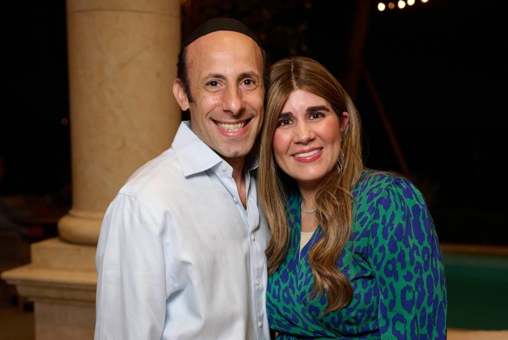 Close-up of two adults smiling for a photo at an outdoor evening event.