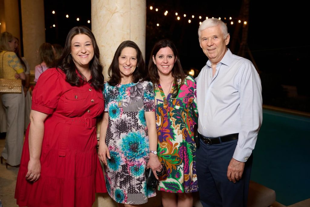 Four adults smiling for a photo at an outdoor evening event.