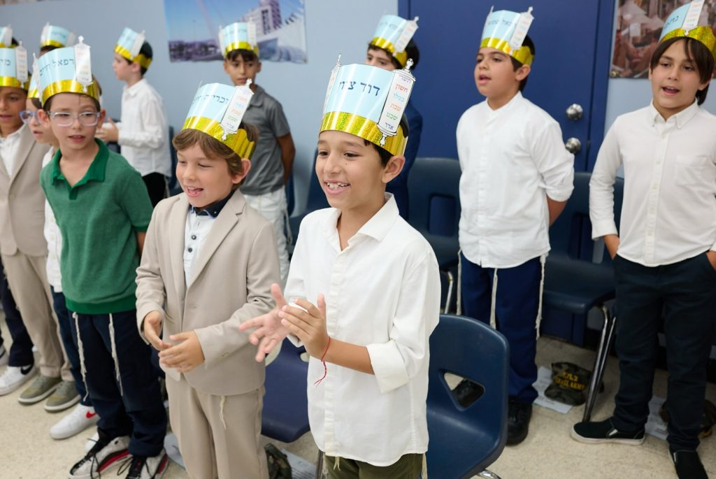 Group of children singing and clapping joyfully.