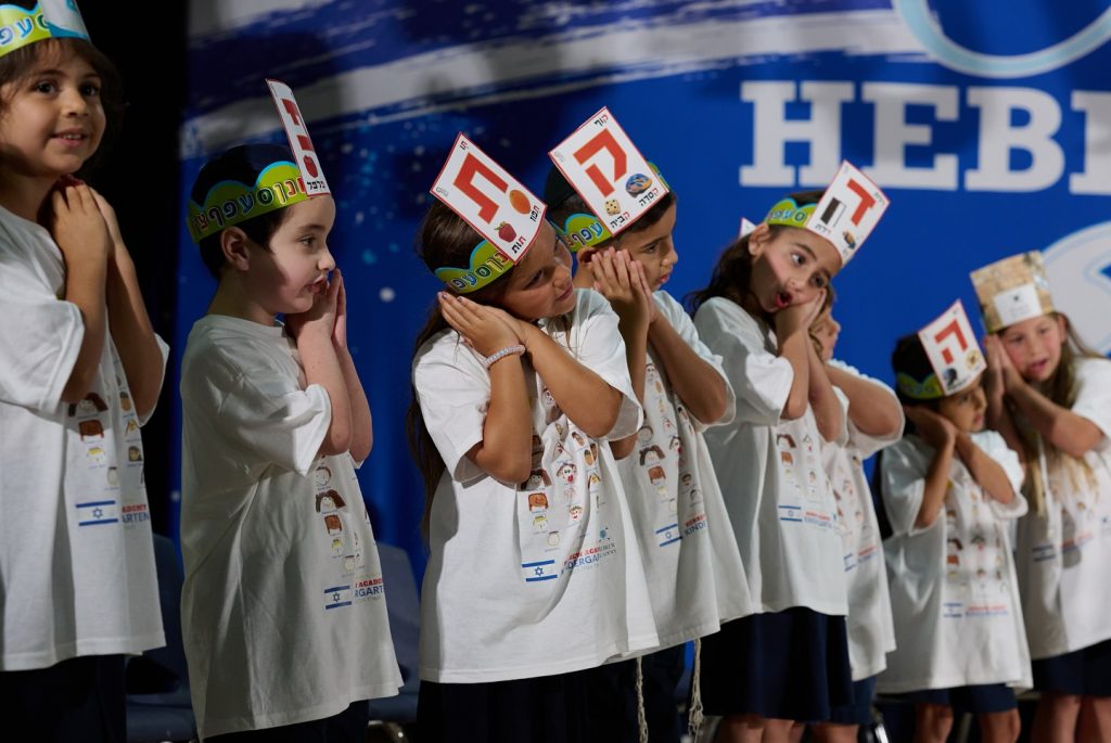 Group of small children singing a sleep song, with their hands mimicking sleeping gestures.