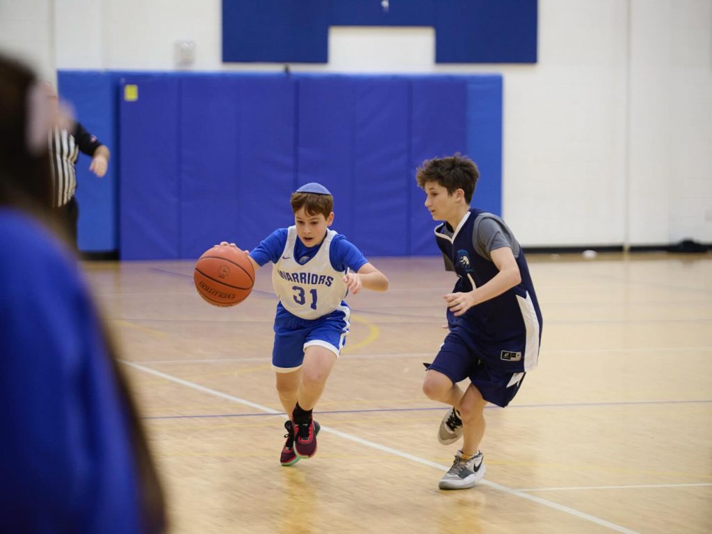 Two boys playing basketball; one dribbling the ball with focus