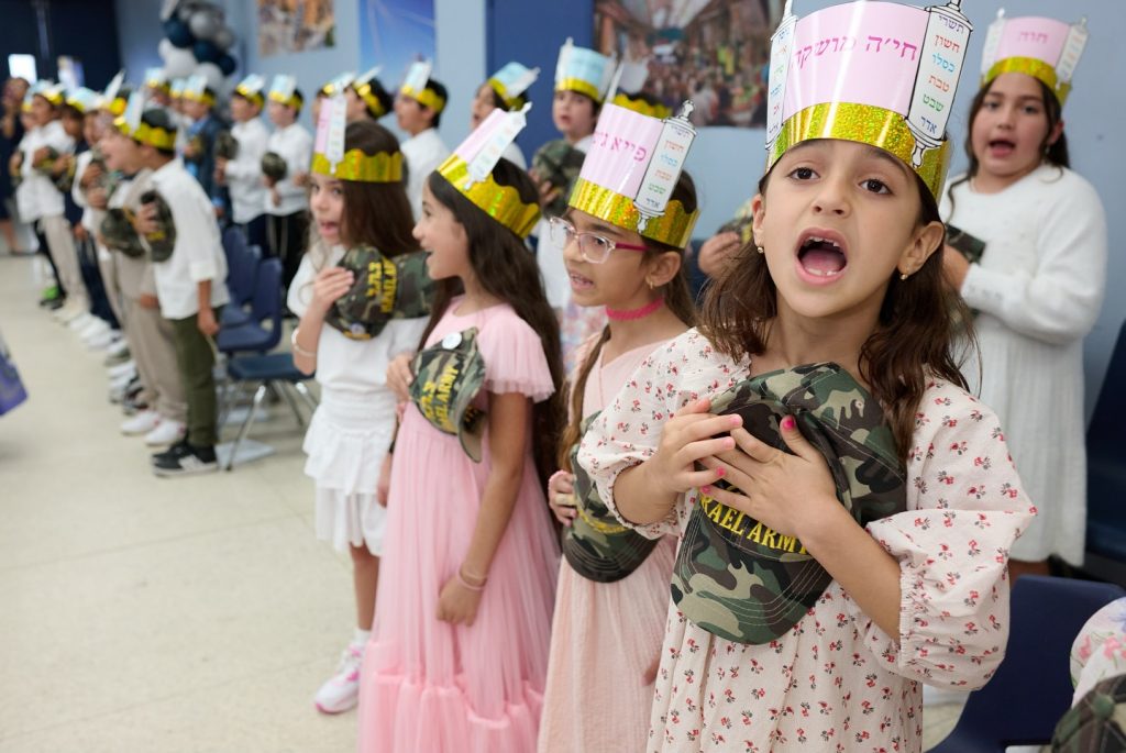 A group of children singing together in a classroom.