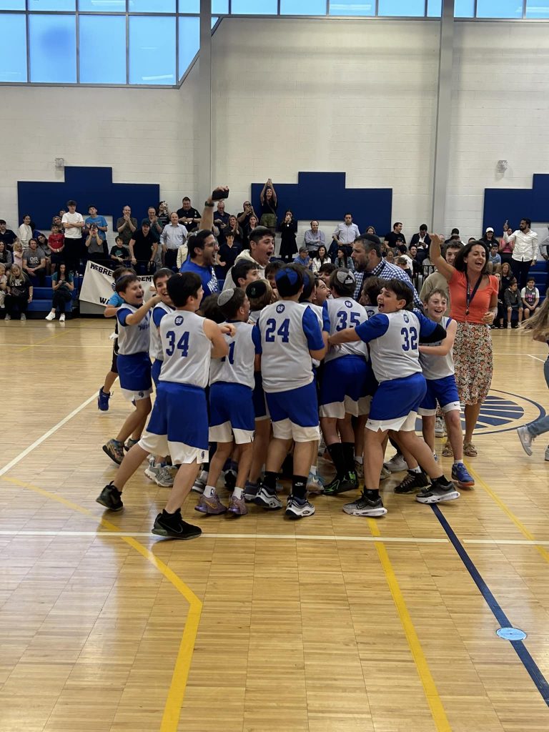 Children celebrating a basketball win with their trainer, showing excitement and joy.