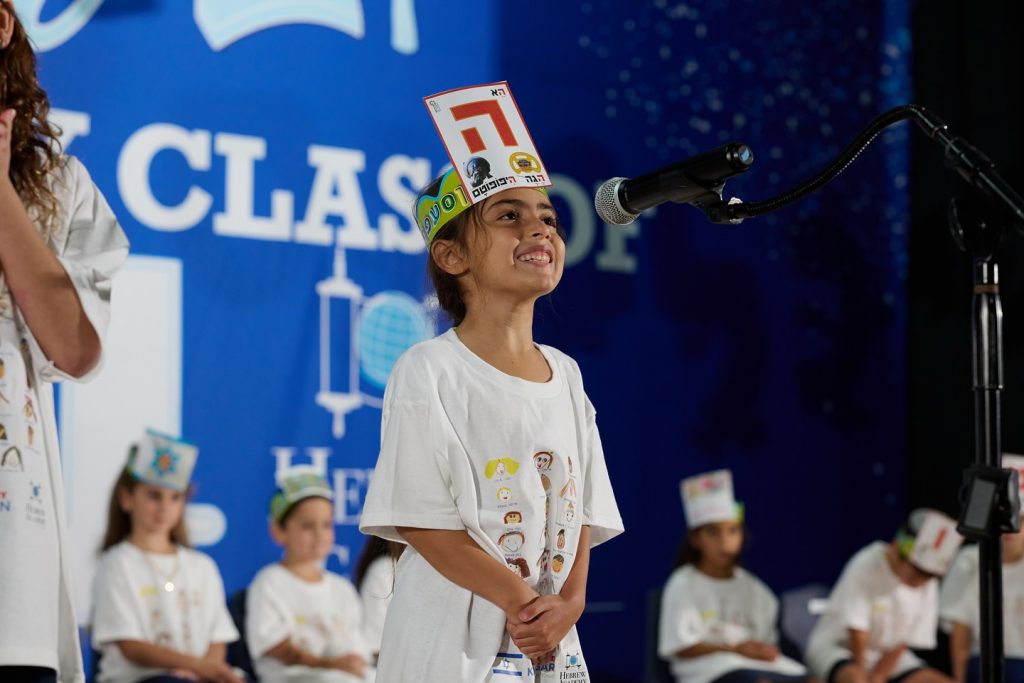 A small girl singing into a microphone at an event.