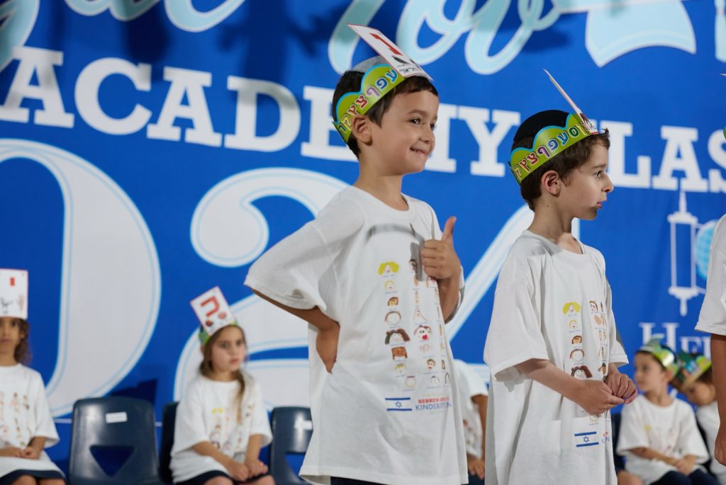 Two children at an event, with one showing a thumbs-up and smiling happily.