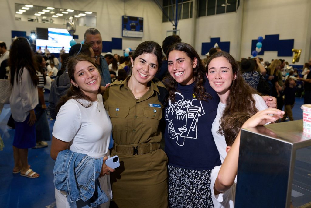 Four girls smiling and taking a photo on a large basketball court indoor.