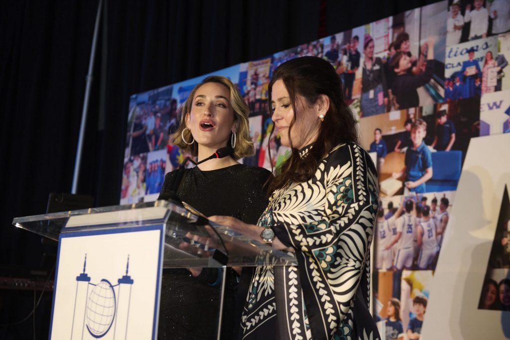 Two women standing at a microphone at Hebrew Academy's 76th Annual Light event.