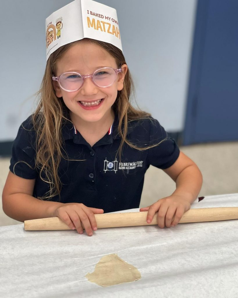 Happy kid smiling while making his own Matzah at a workshop.