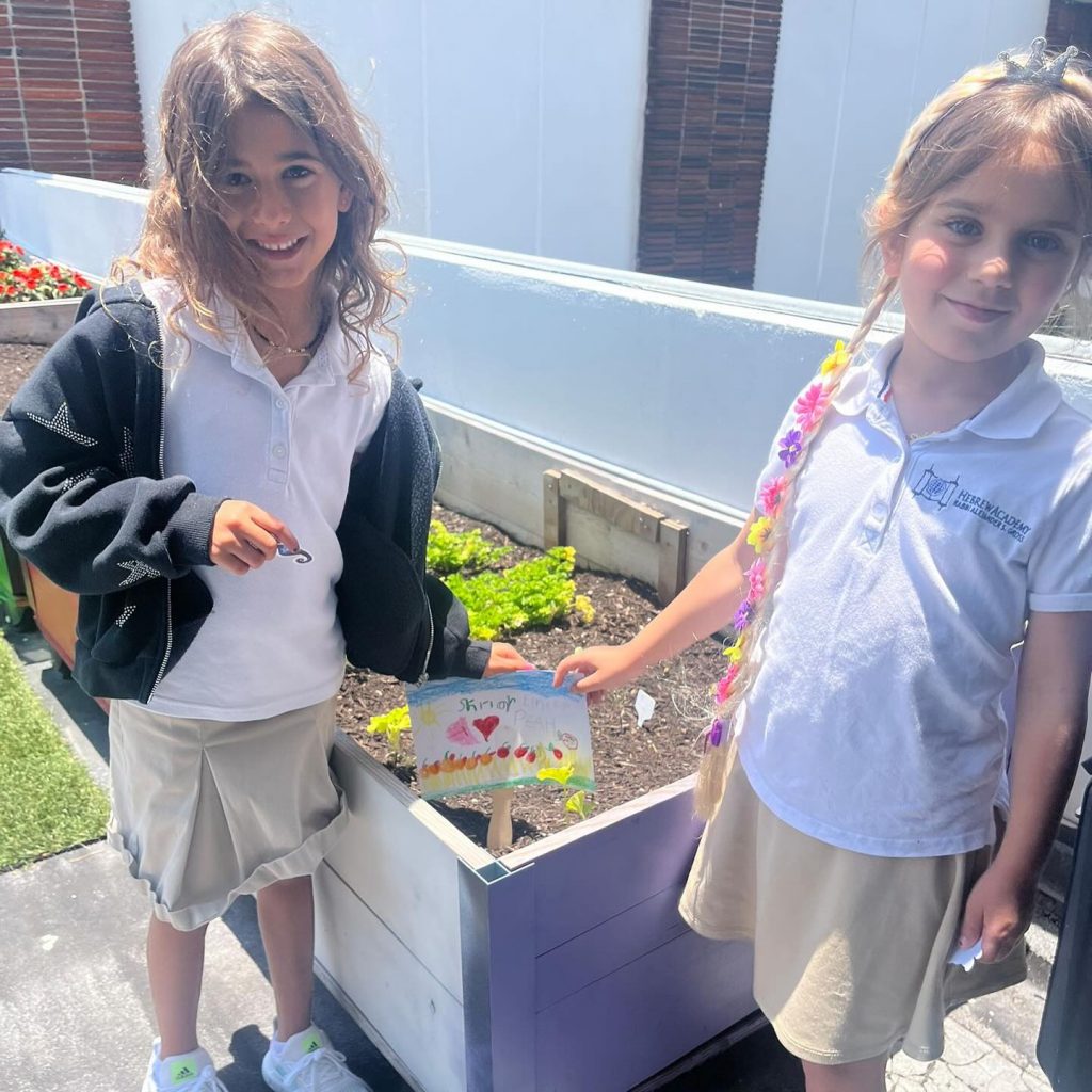 Two girls, smiling and proudly showing and holding their drawing.