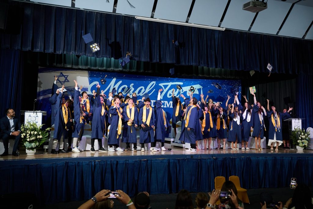 Graduating students tossing their hats on stage in celebration.