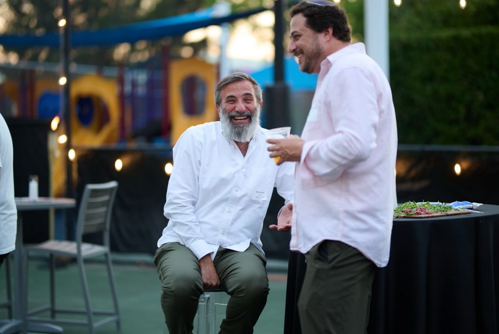 Two men in white shirts enjoying their drinks at a party.