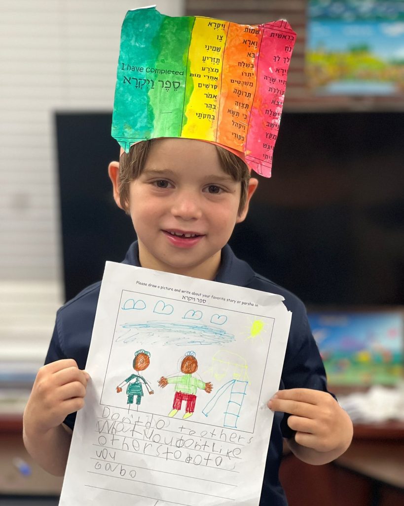 Close-up of a boy proudly showing his drawing, looking happy.